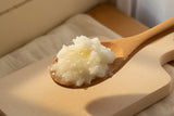 A wooden spoon of firm coconut oil, ready for cooking