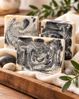 Three handmade colloidal silver and activated charcoal soap bars on linen