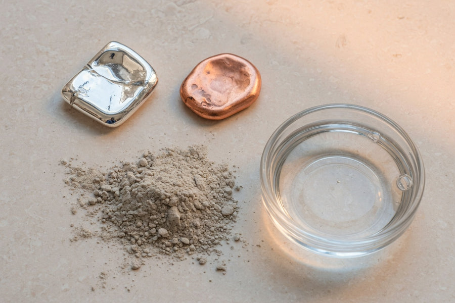 Silver, copper, clay and a dish of clear water on limestone.