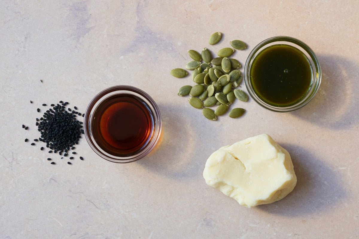 Nigella seeds, pumpkin seeds, oils and cacao butter on limestone.