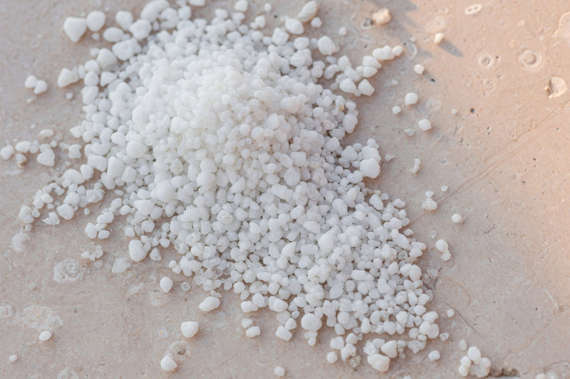 White granular creatine powder on pale limestone.