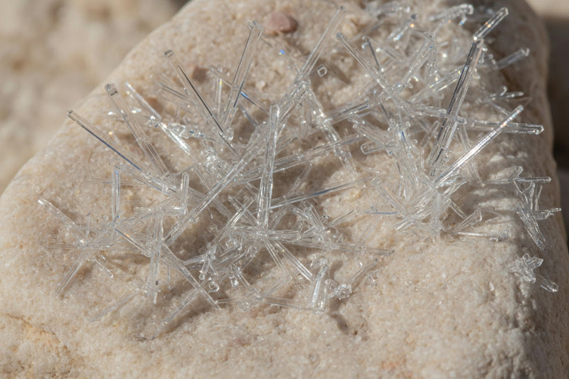 Clear needle-like MSM crystals on pale limestone.