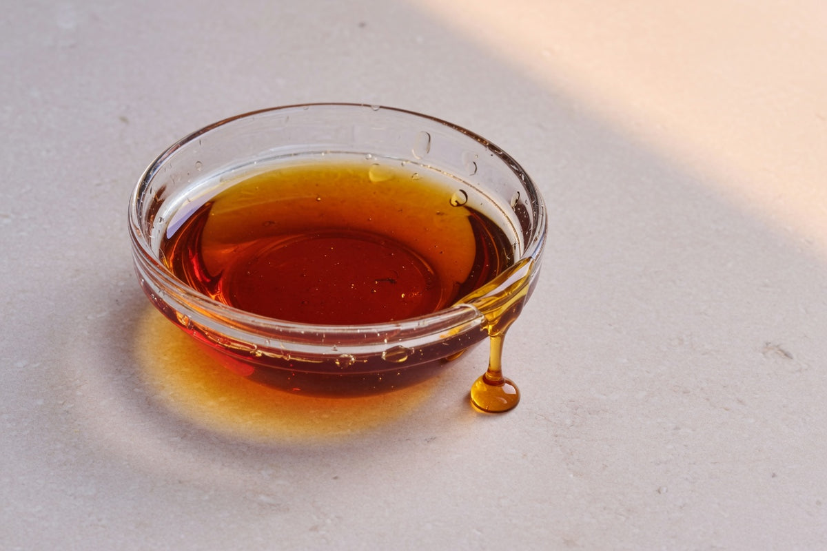 Viscous golden oil in a glass dish on limestone.