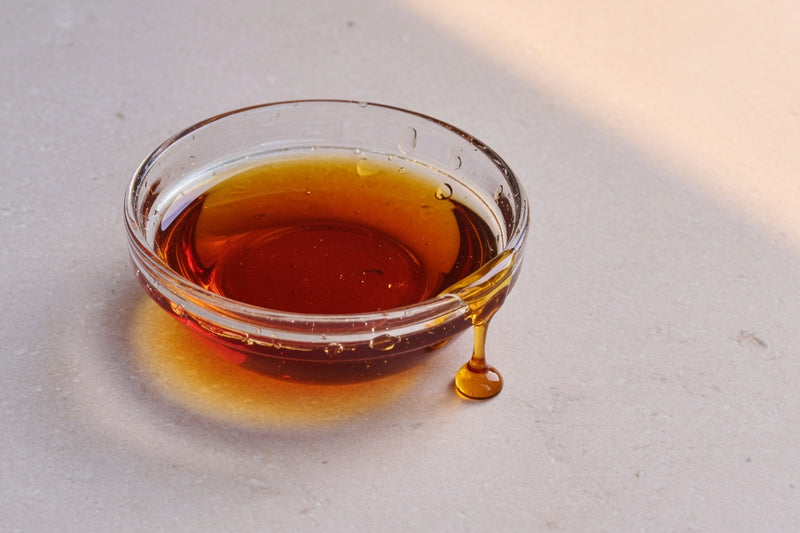 Viscous golden oil in a glass dish on limestone.