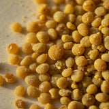 Close-up of organic bee pollen granules showing gold and ochre pellets